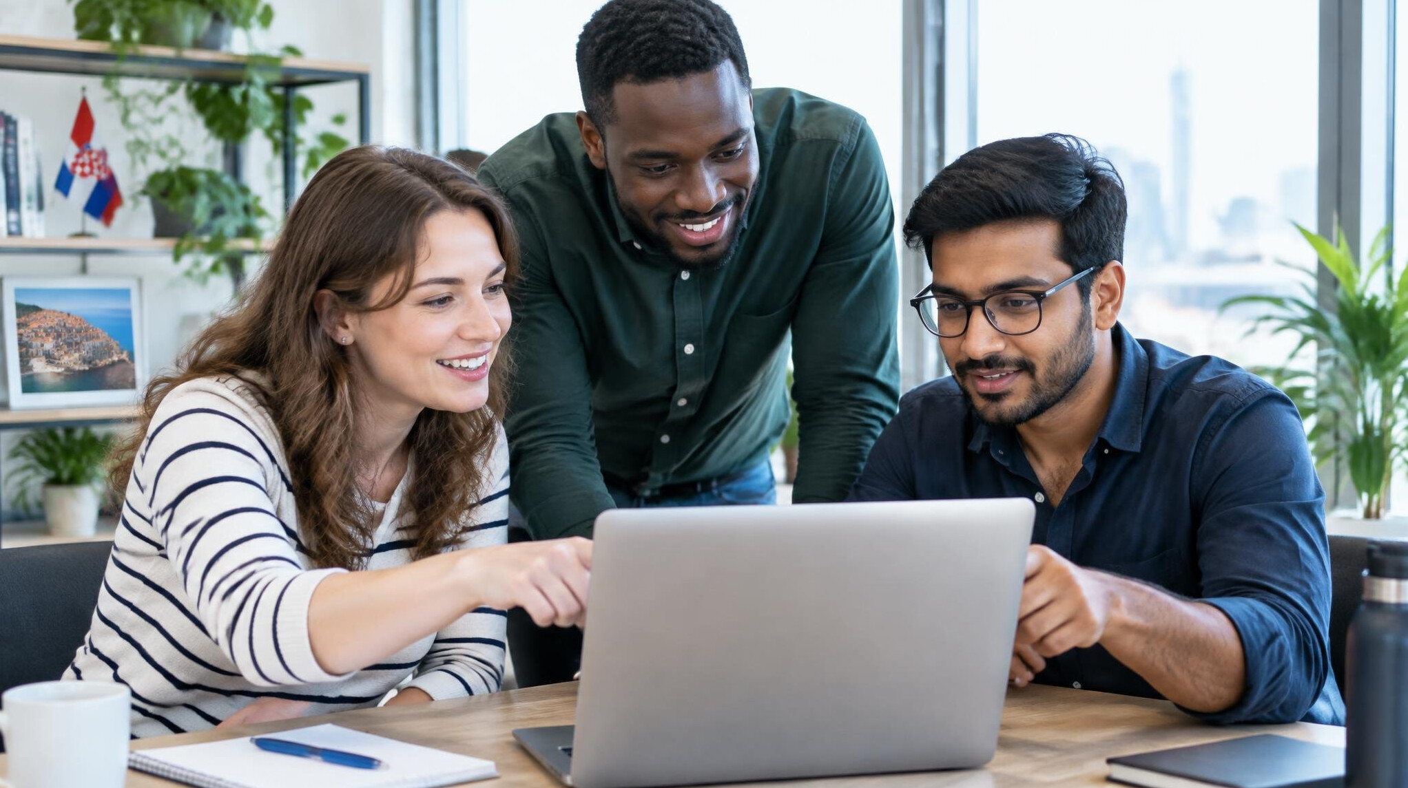 Group of people collaborating around a laptop in a bright office